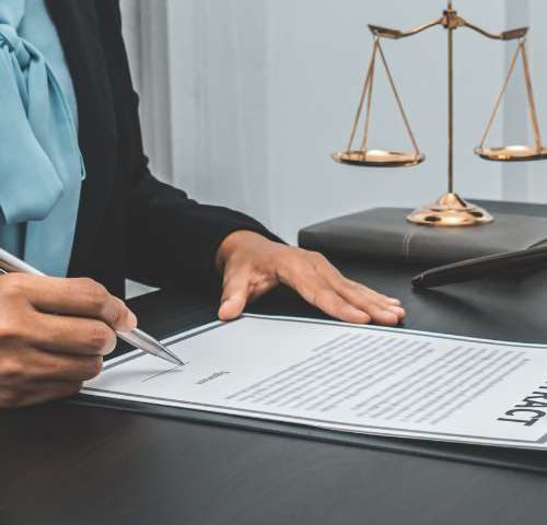 Firma de documentos junto a una balanza de la justicia